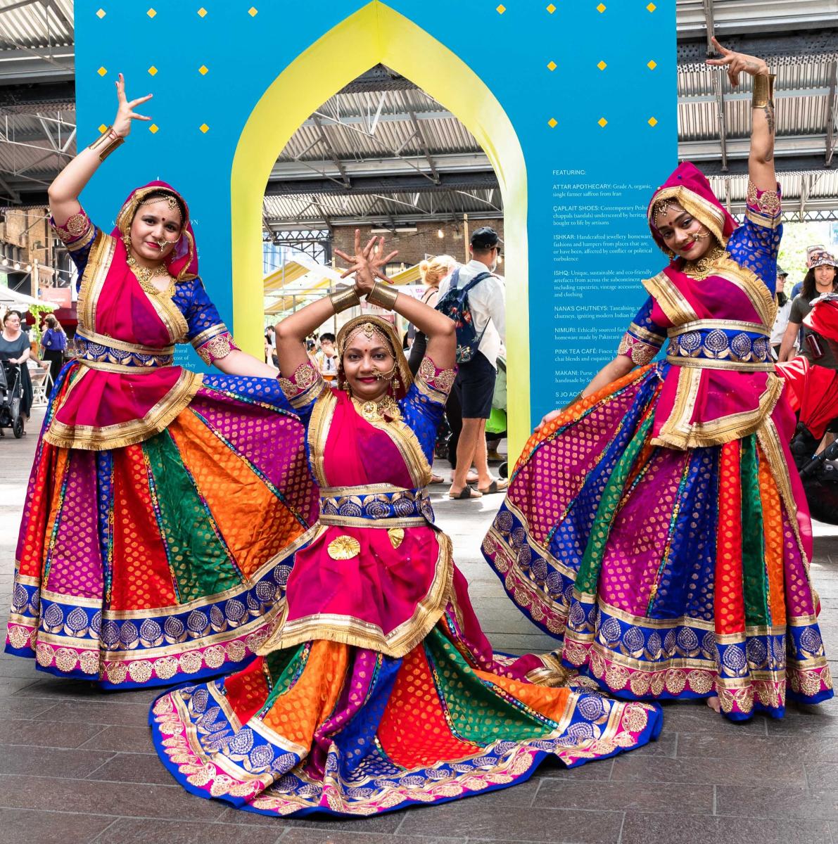 Image of three dancers dressed in vibrant colours in traditional patterns and shapes