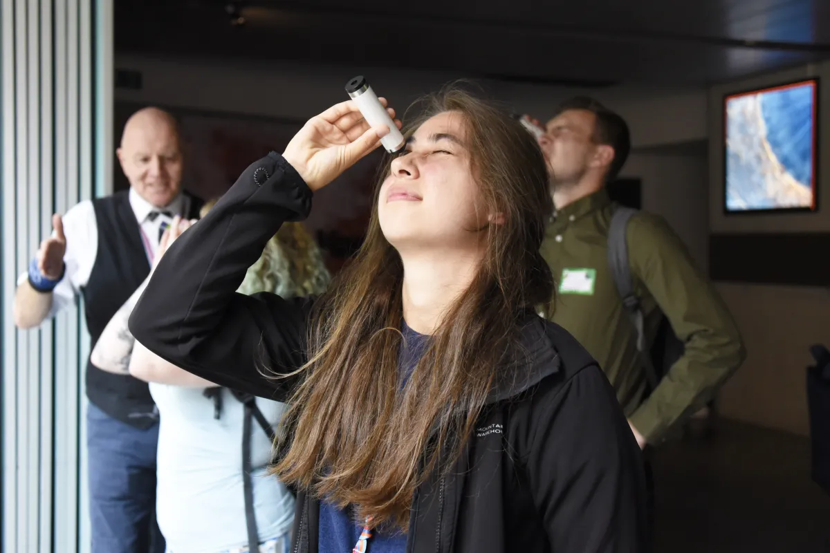 A woman looks through a pocket spectroscope.