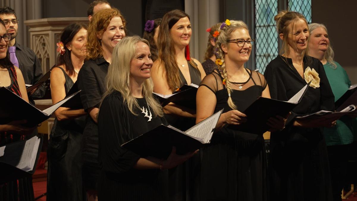 Image of a choir of people holding lyric sheets and smiling