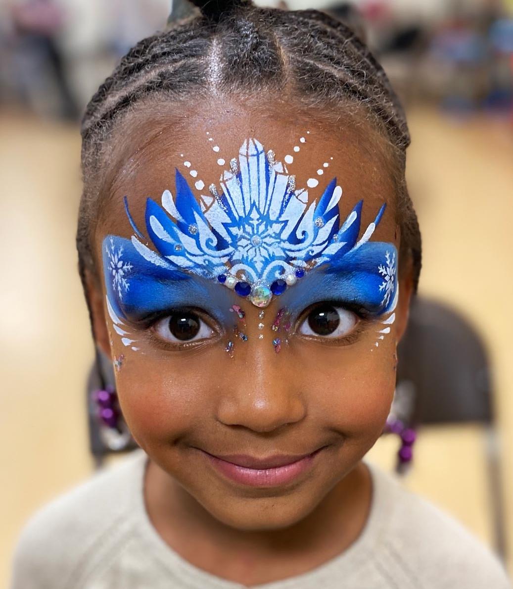 Image of a child with a big snow crystal design painted on her upper face