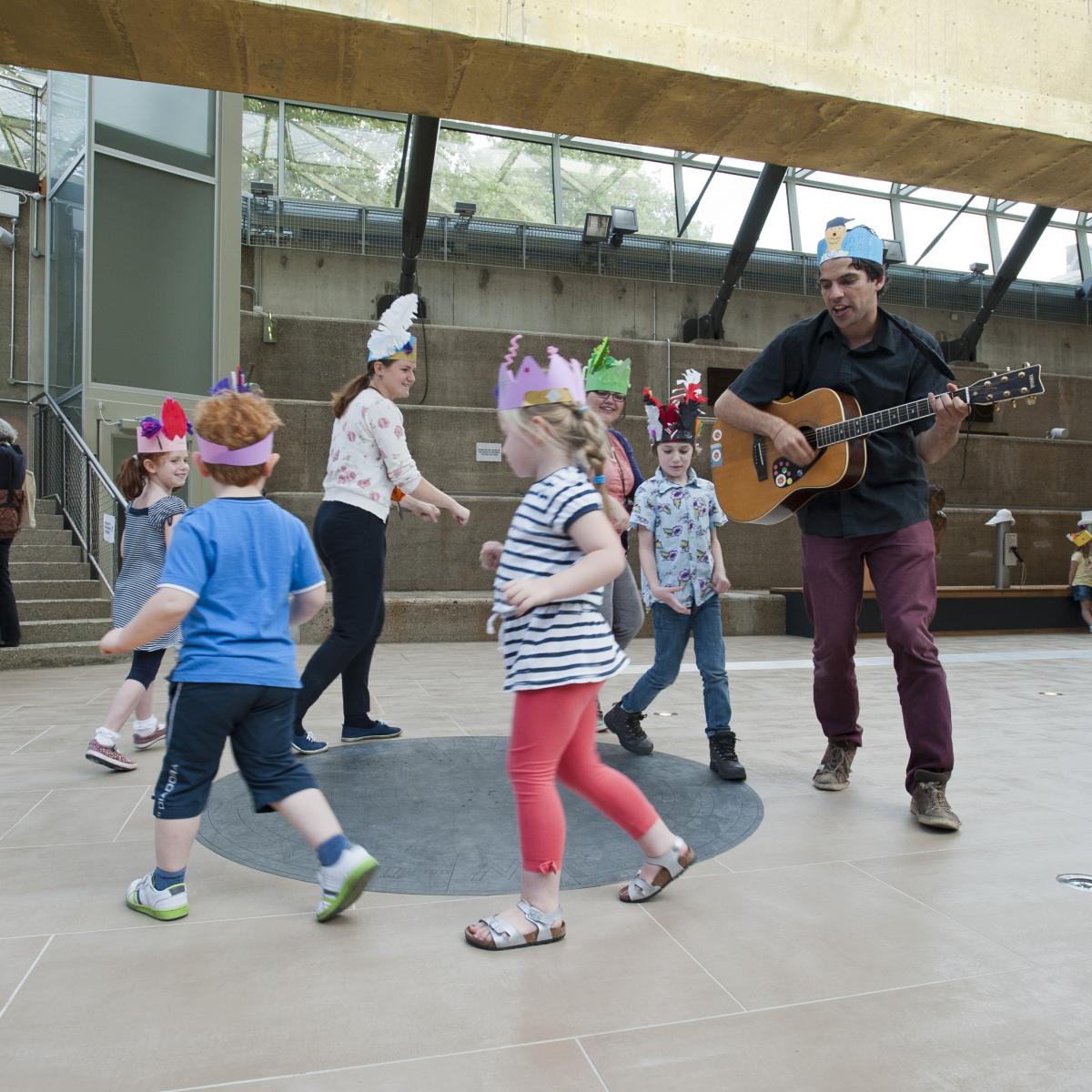 Family workshop at Cutty Sark - group of children and guitar player