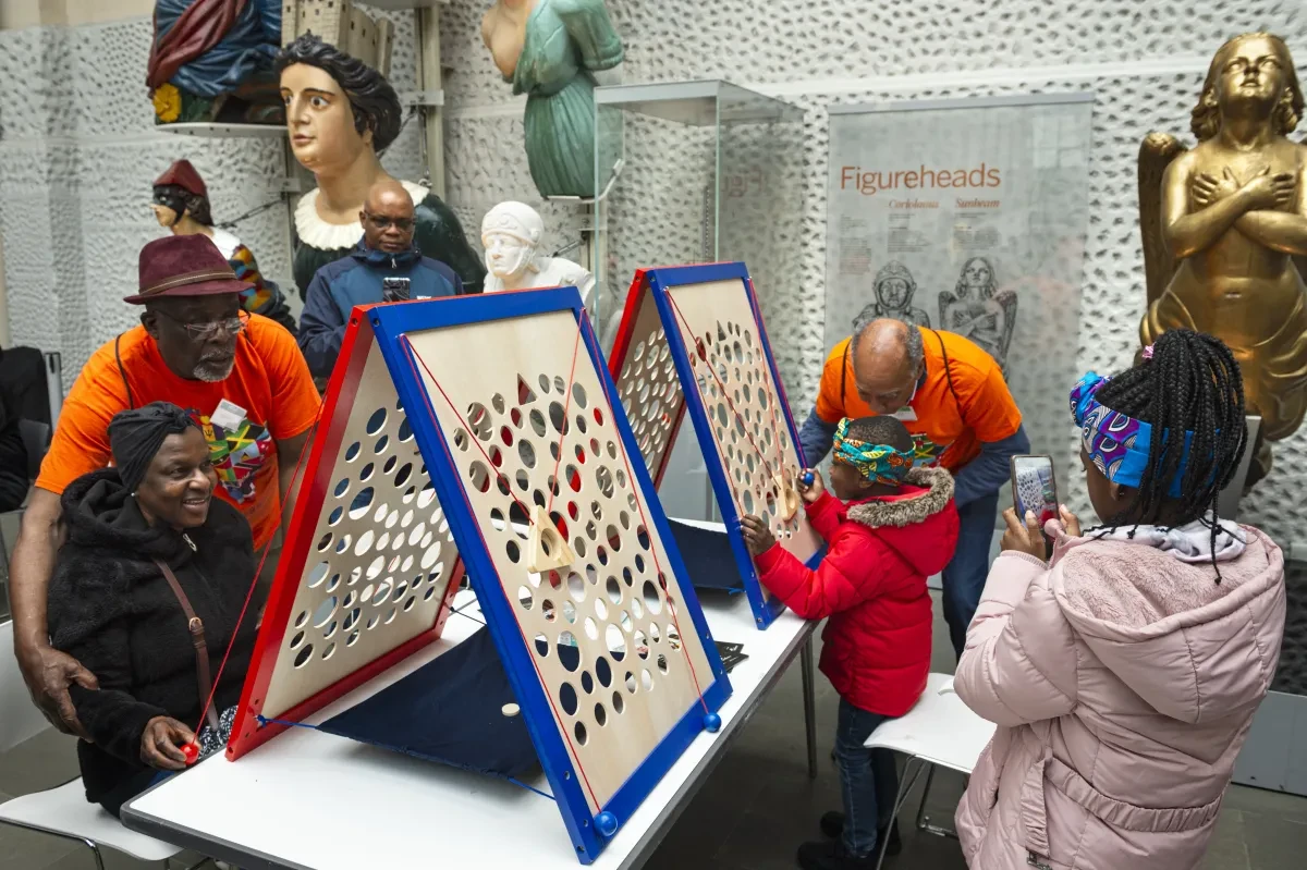 People playing a game with boards propped up which have holes in them