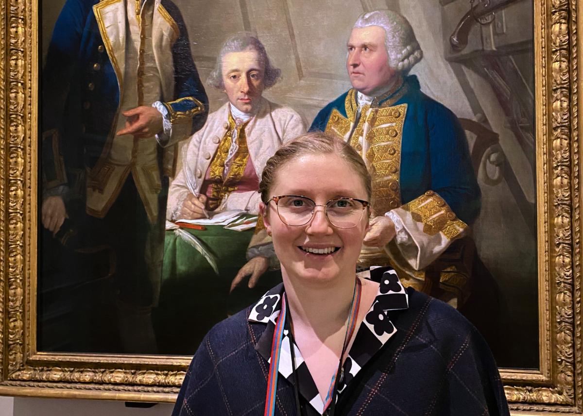 An art curator smiling in front of an oil painting