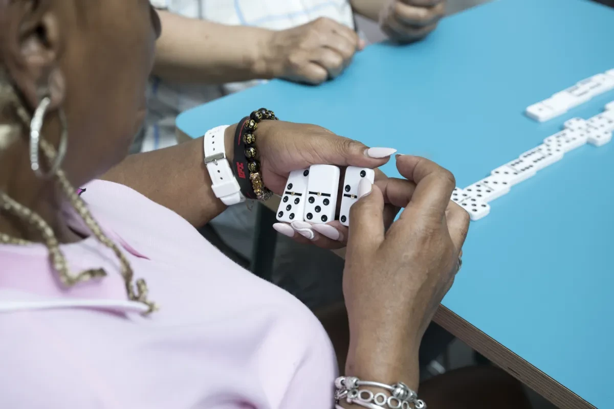 A woman looks at the dominoes she is holding in her hand during a game