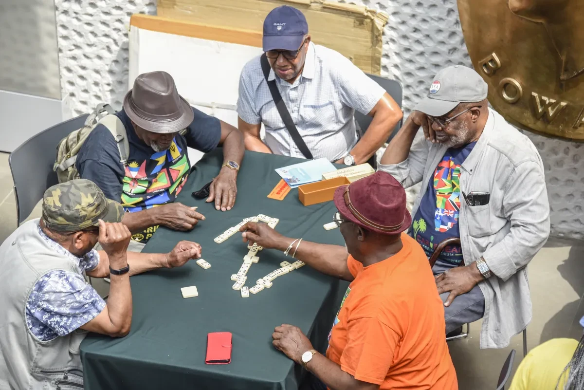 Image of five men around a table playing dominos