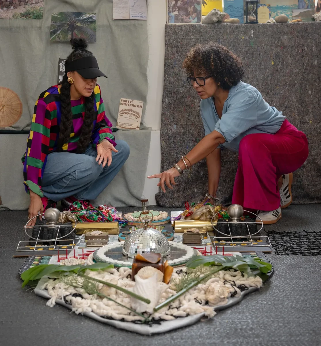 Two artists wearing colourful clothing look an at artwork