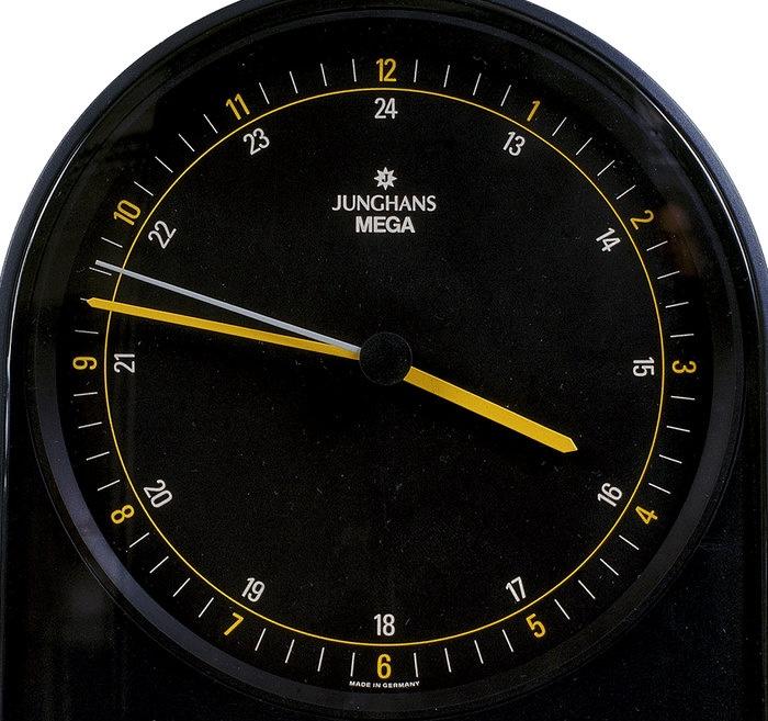A black clock face with yellow hands and numbers round the dial
