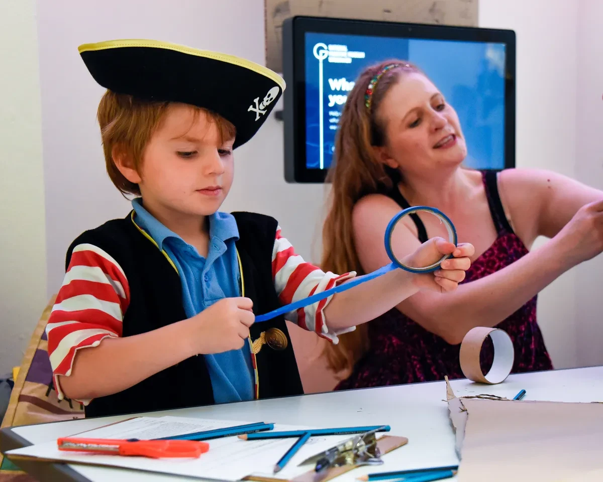 A boy dressed in a pirate costume takes part in a craft activity at the National Maritime Museum
