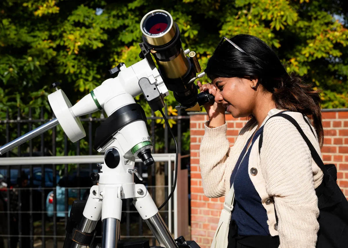 A woman looks through a telescope during a daytime observing session at Royal Observatory Greenwich