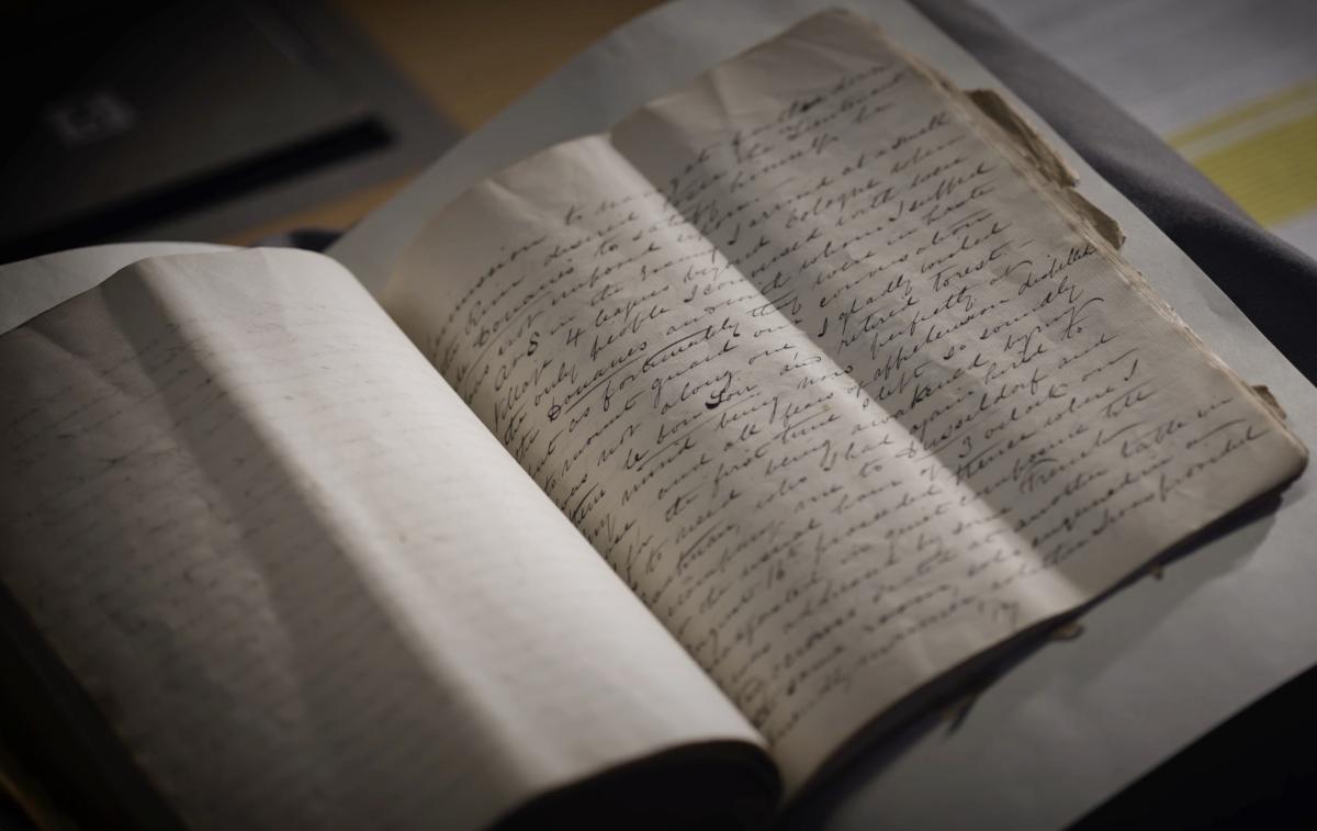 A handwritten manuscript sits on a cushion in a library