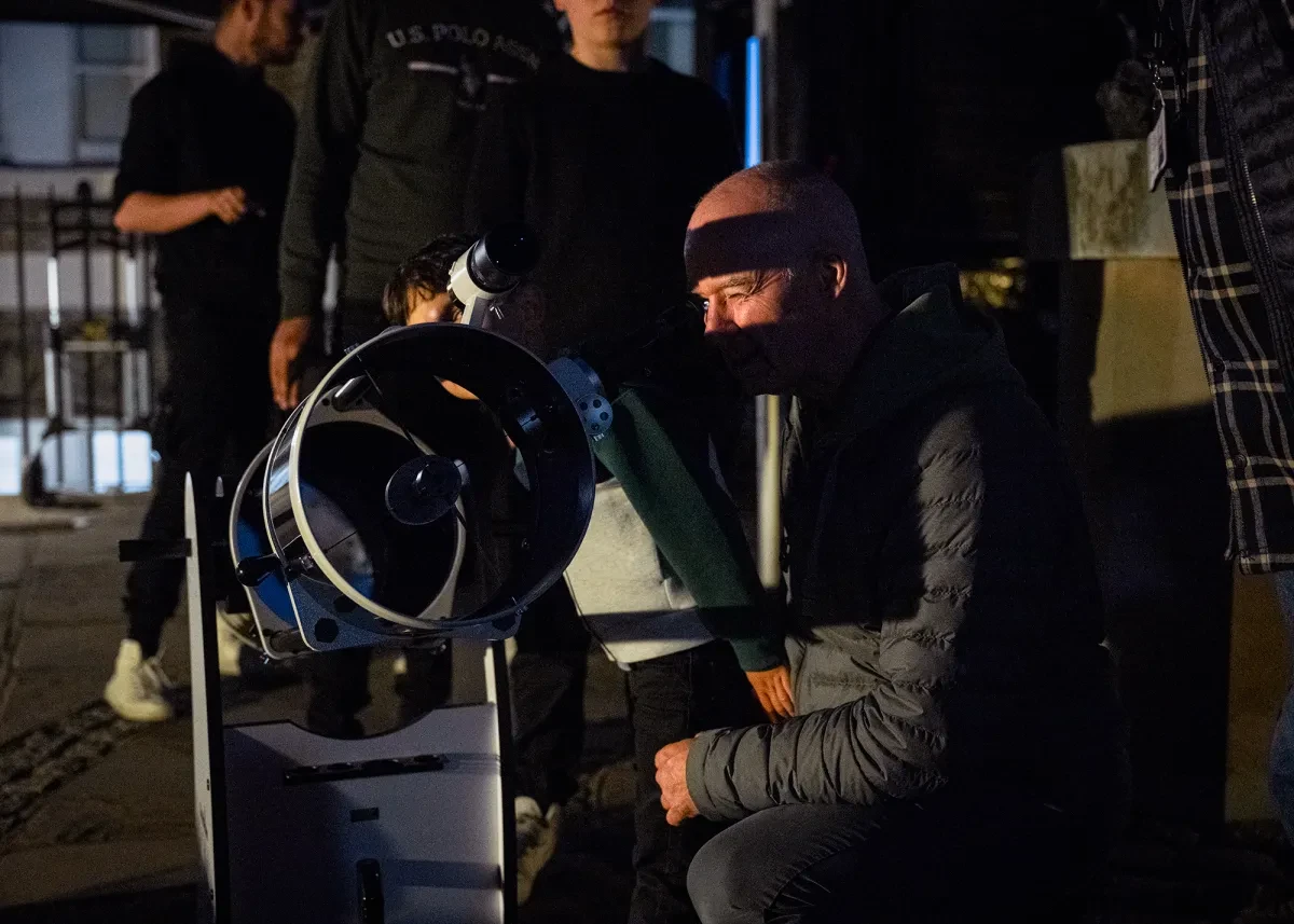 Night-time observing session at the Royal Observatory. A man and a boy are looking through a large telescope