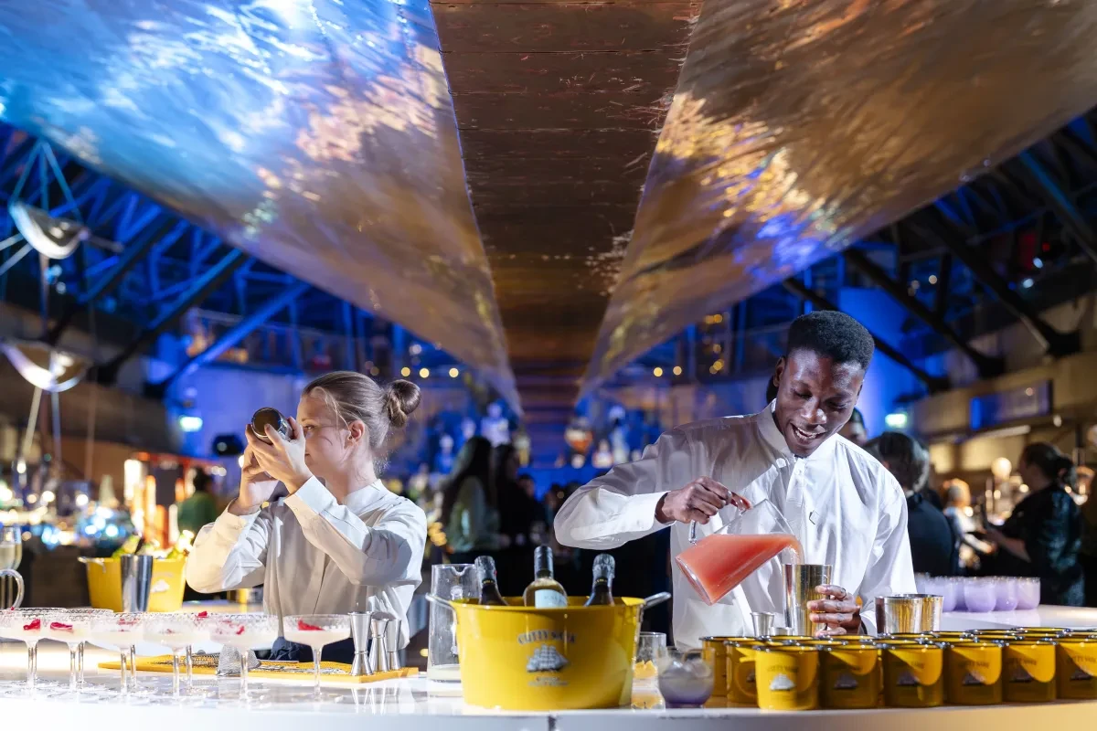 Moving Venue Staff serving cocktails on the central bar under the hull of Cutty Sark