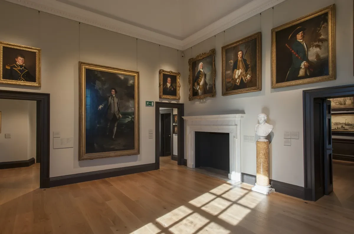 A room hung with paintings and a bust