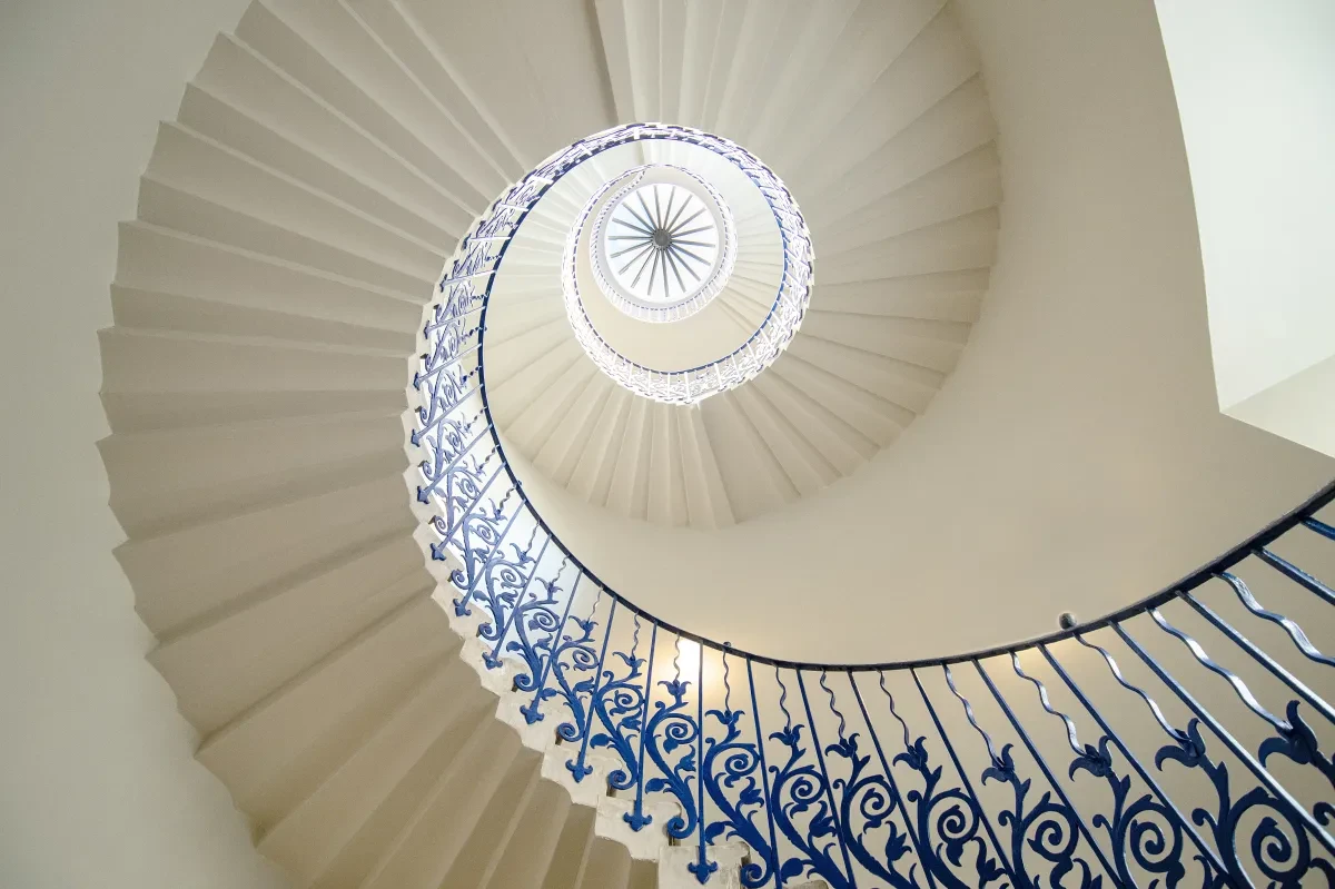 A spiral staircase with blue banisters featuring lily details