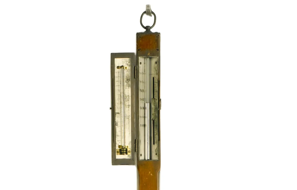 The top part of a wooden stick barometer from around 1800. A brass scale and thermometer is housed on the top of a wooden stick