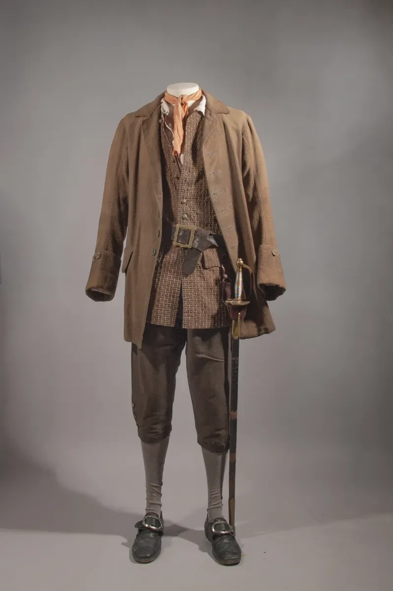 Original costume for Will Turner from Pirates of the Caribbean: The Curse of the Black Pearl. The costume includes a brown cotton jacket, waistcoast and breeches. A sword hangs from a leather belt around the waist