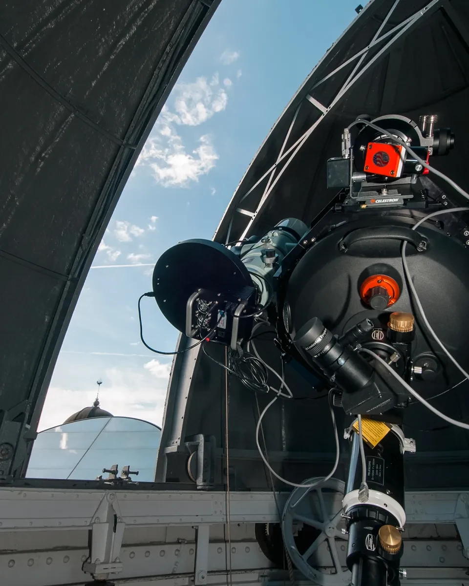 A large telescope under a partially open domed roof.