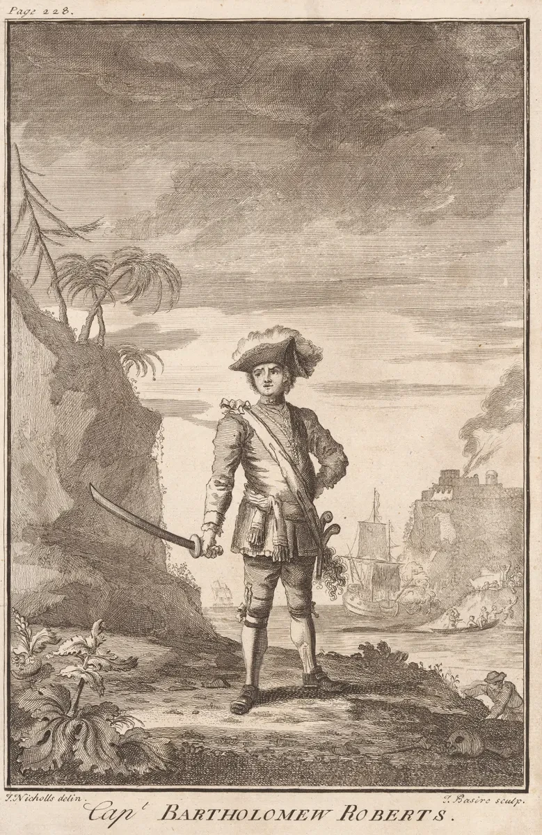 Historic illustration of the pirate Bartholomew Roberts. He is standing dramatically at the shoreline, holding a sword in his right hand and wearing a tricorn captain's hat