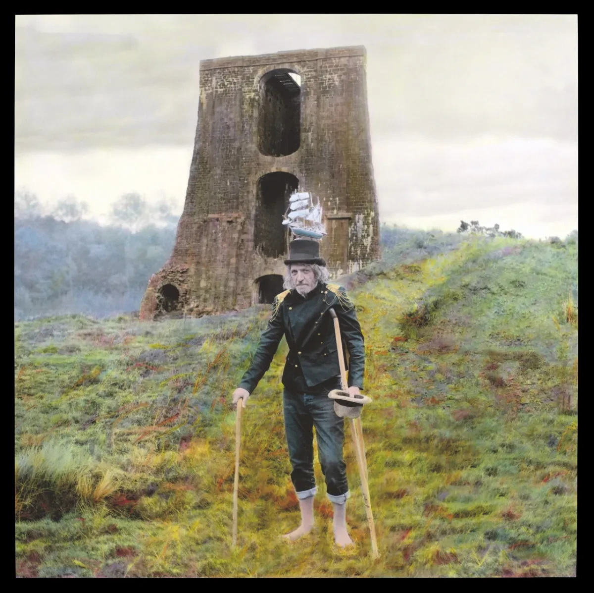 A man stands in heathland with the remains of a bridge behind
