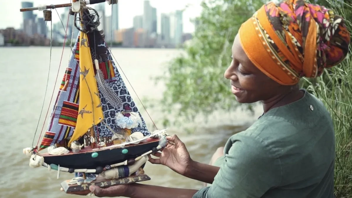 artist Remiiya Badru holding a brightly coloured model boat