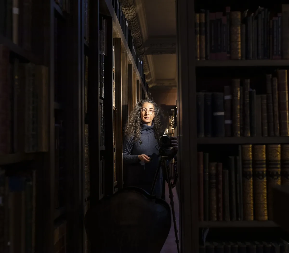 photo of a women in a library very dark except for her face