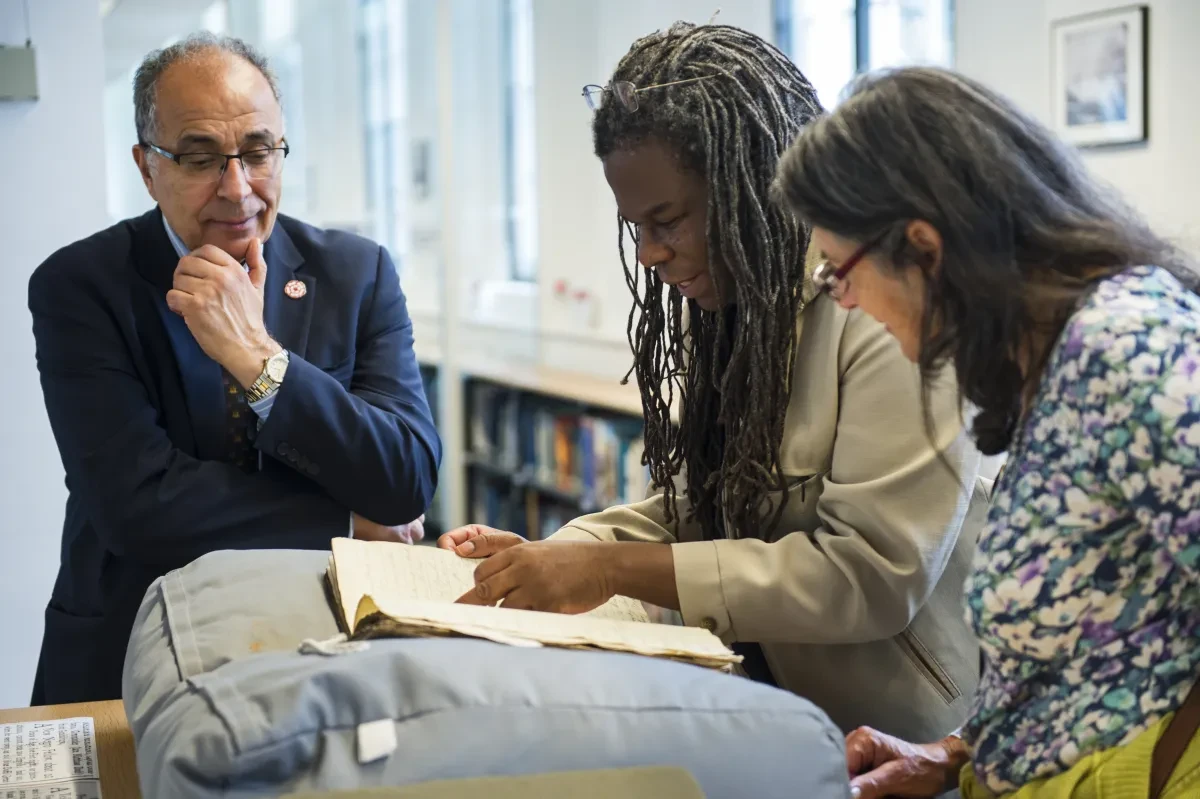 Two men and a woman looking at a manuscript in the Caird Library
