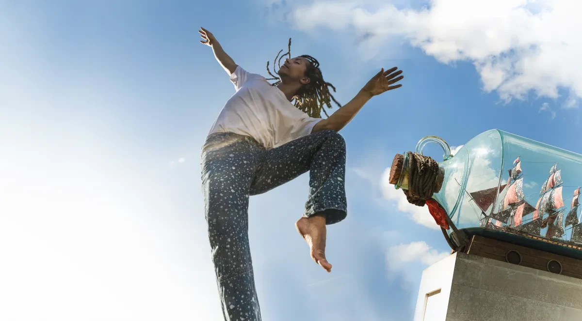 A dance leaps beside Nelson's Ship in a Bottle sculpture