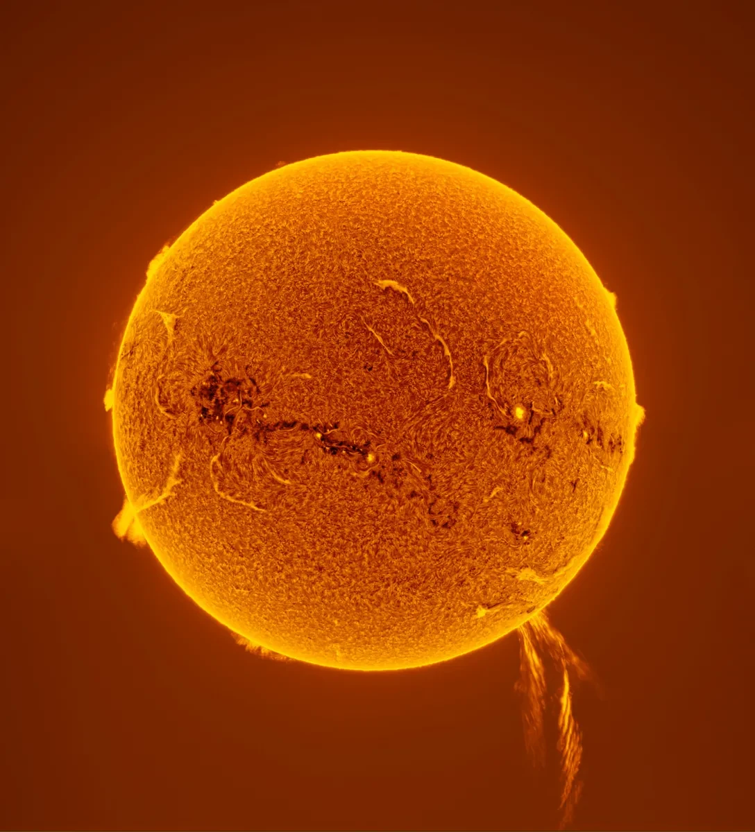 Photo of the Sun in bright oranges and yellows with a solar prominence coming out of the bottom of it