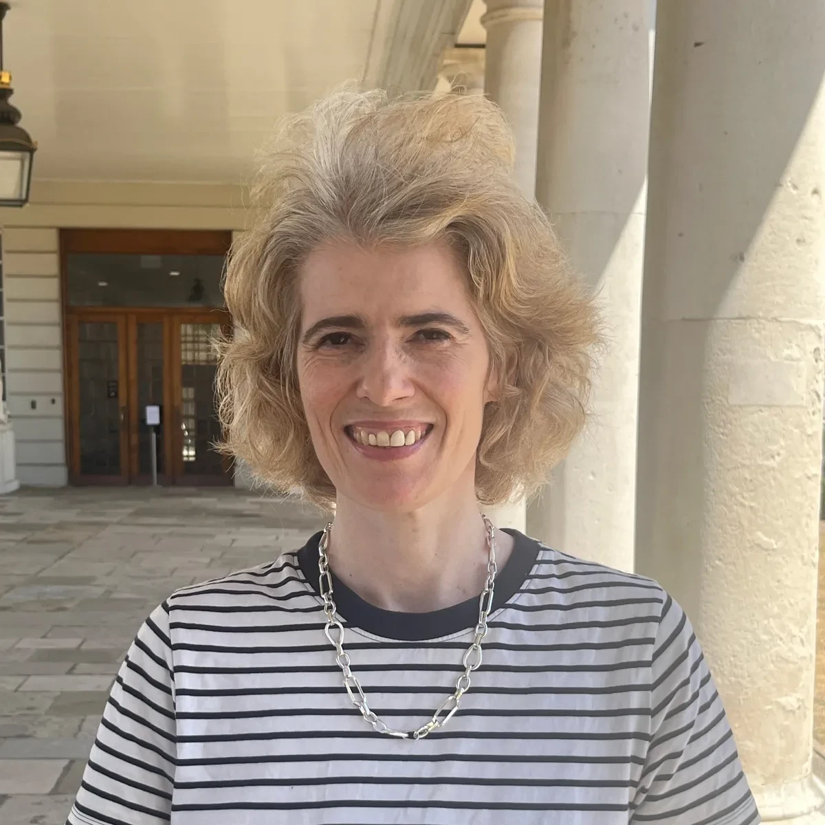 Headshot of curator Claire Warrior. She is wearing a navy and white striped top and a silver necklace
