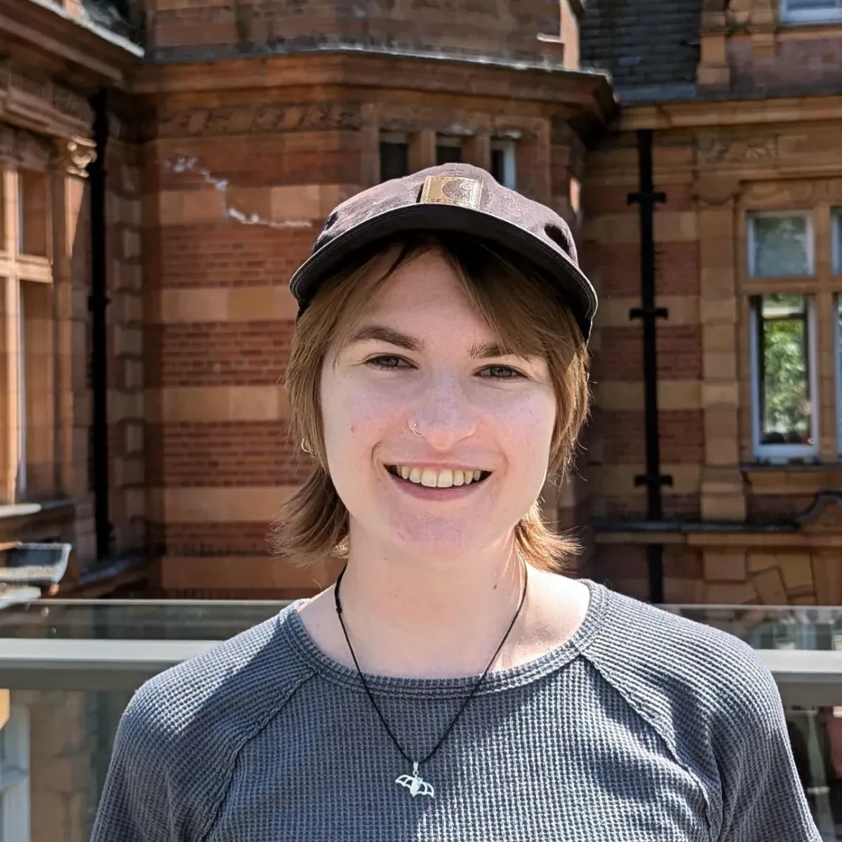 Astronomer Imo Bell smiles while standing outside one of the buildings at Royal Observatory Greenwich
