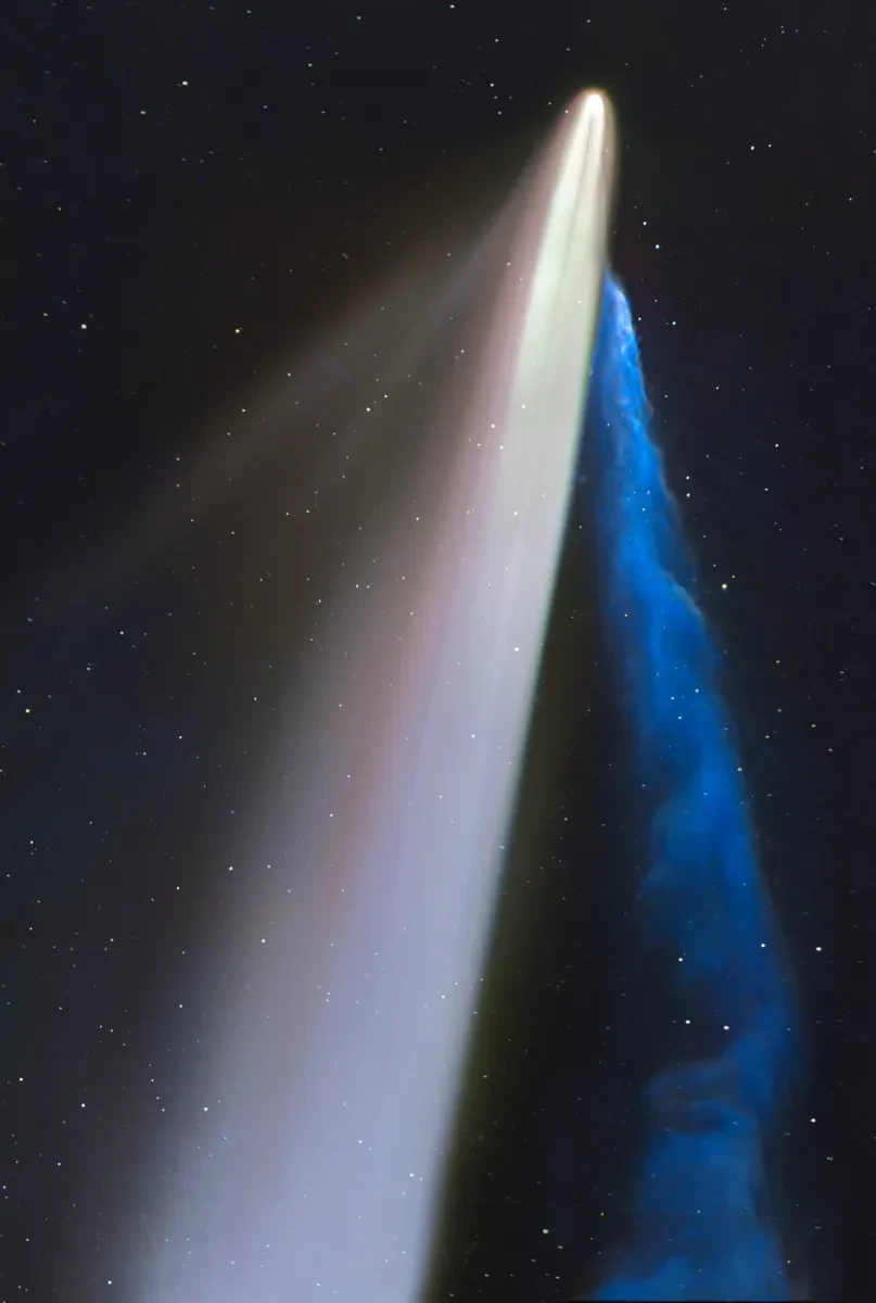 A comet with a long dust tail and a cloudy blue ion tail in a black, starry sky.