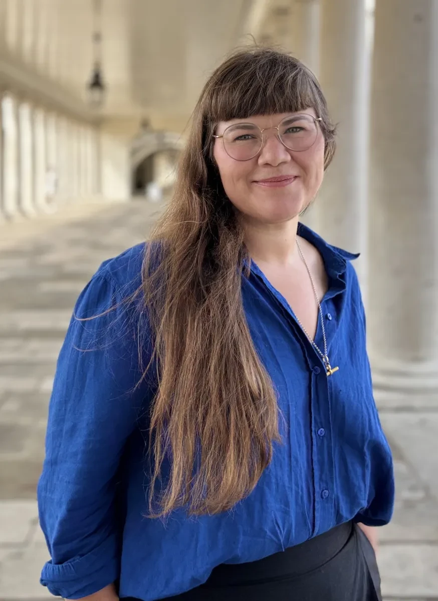 Headshot of curator Maya Wassell Smith standing in the colonnades at Royal Museums Greenwich