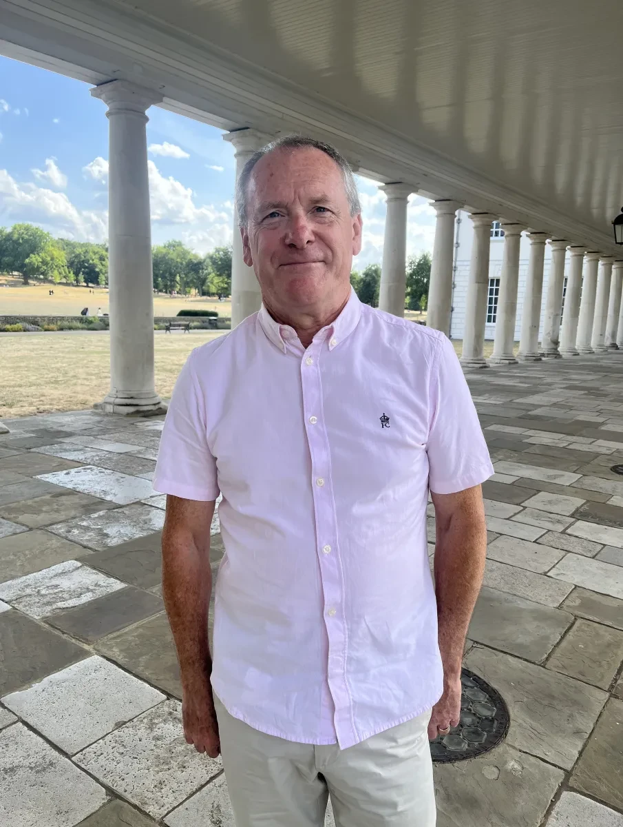 Headshot of curator Simon Stephens standing in front of the colonnades at Royal Museums Greenwich