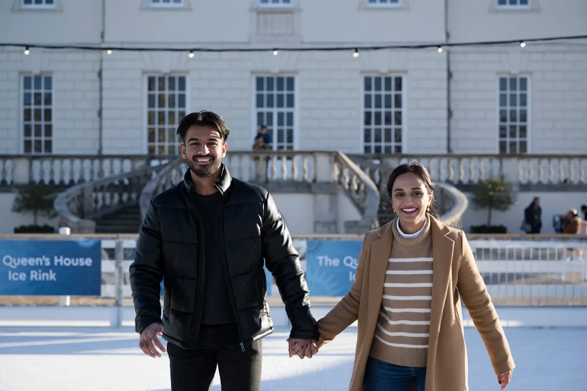 Close up image of a couple skating and holding hands on the Queen's House Ice Rink