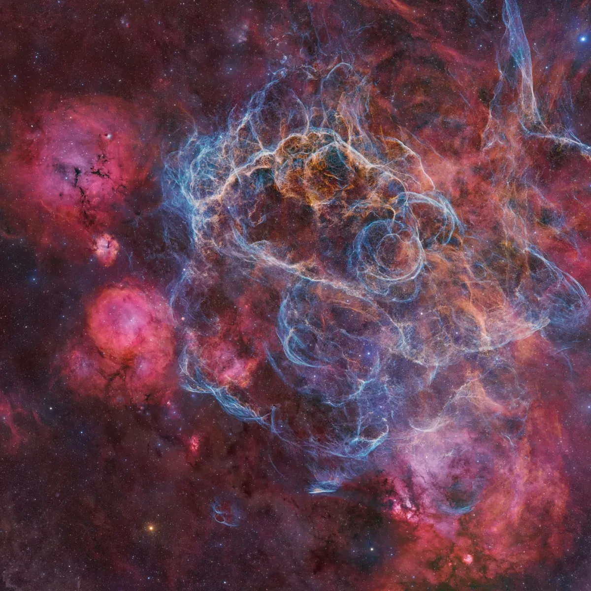 Remains of a massive star stretching across the sky with glowing red, blue and pink gases