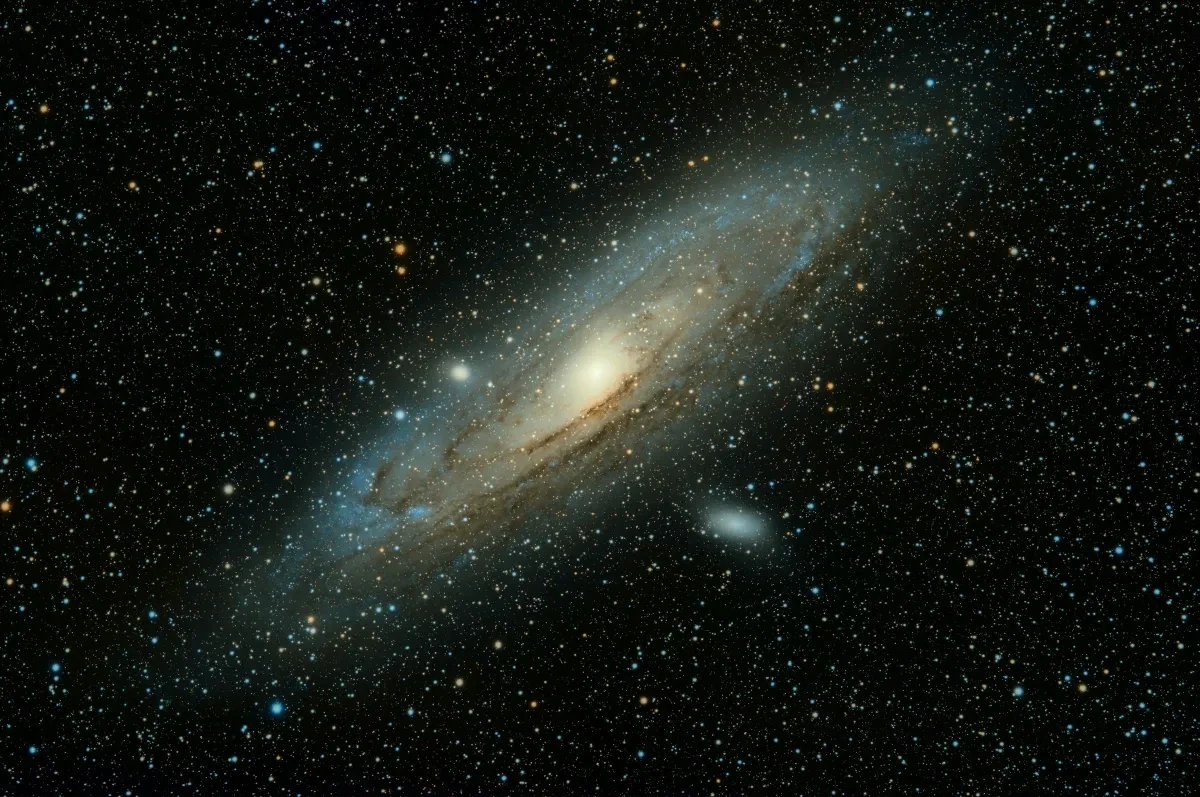 Photo of a spiral galaxy diagonal from our perspective, with a bright yellow core and blue arms