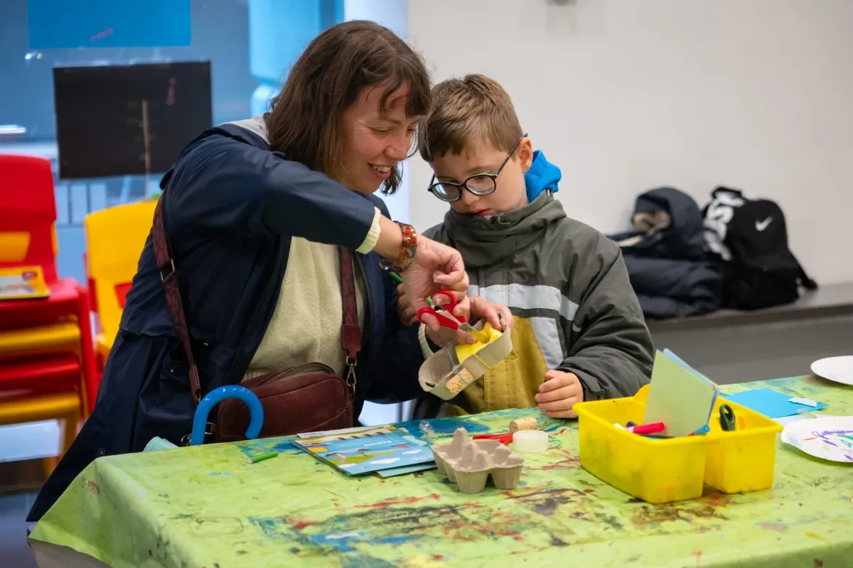 Photo of adult and child leaning towards each other as they craft something