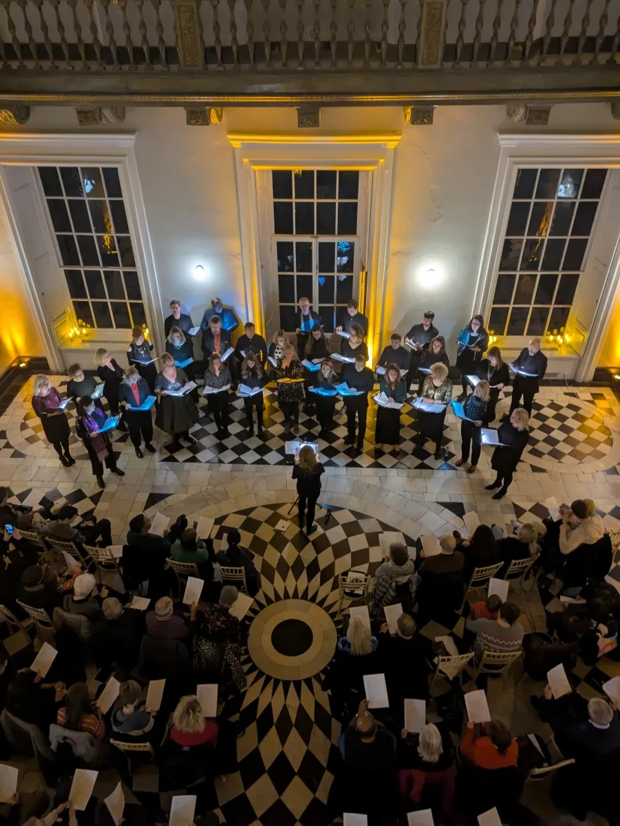 Image of a choir and audience at an evening concert in the Queen's House