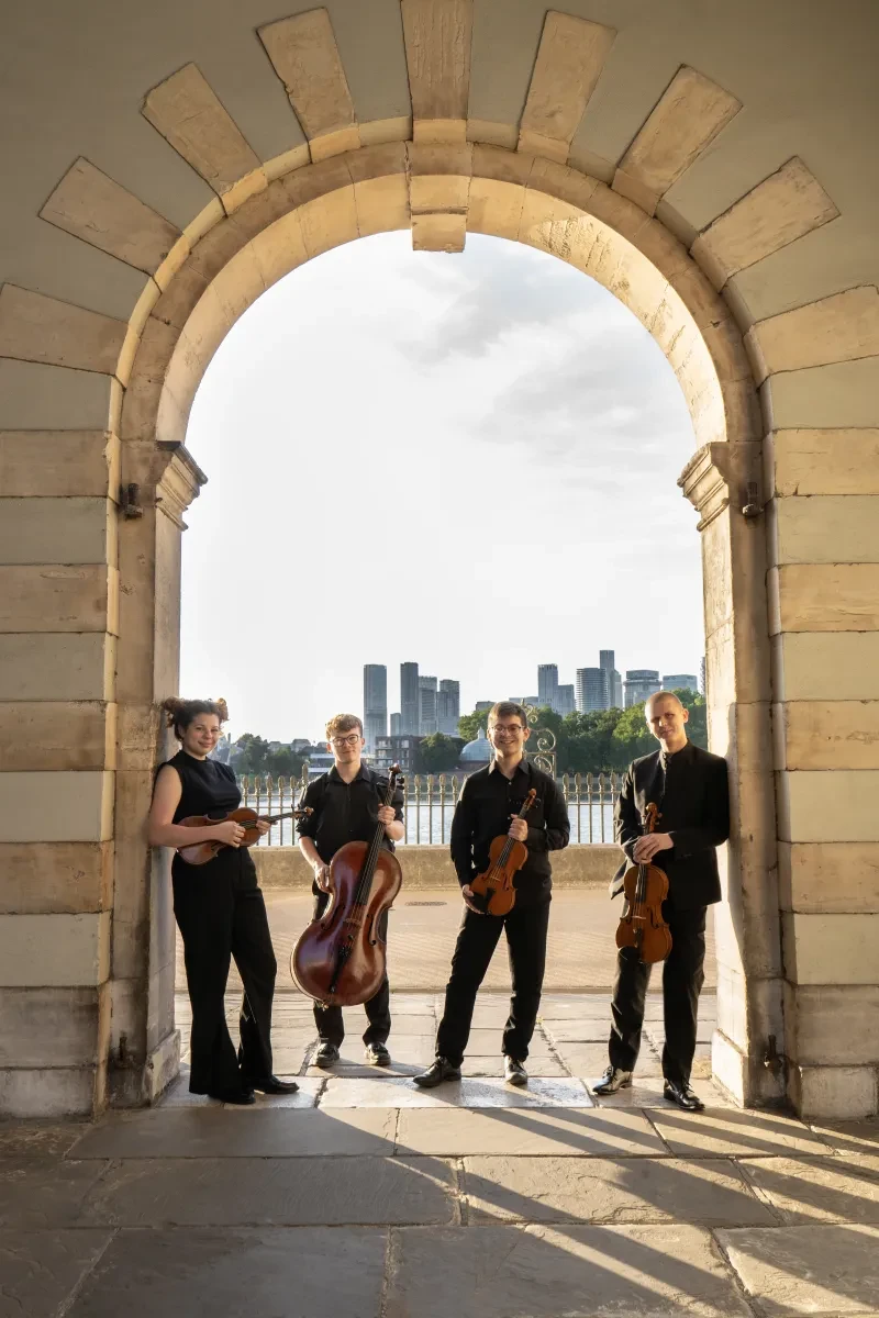 A group of four musicians standing in an arch holding string instruments