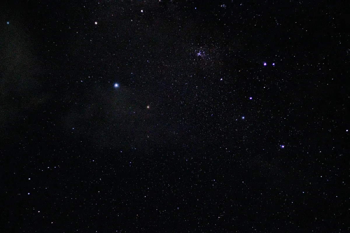 Starry sky with hundreds of small pinpricks of light, and scattered large stars