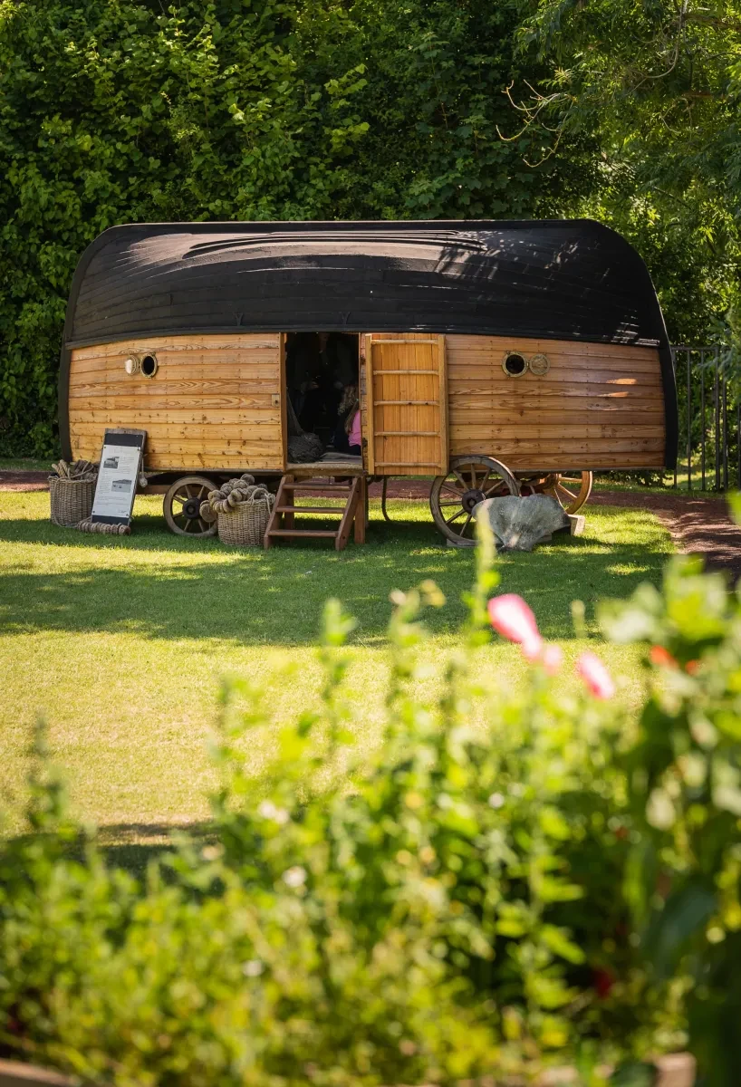 An image of an upside down boat on a bespoke wagon with a door in a field