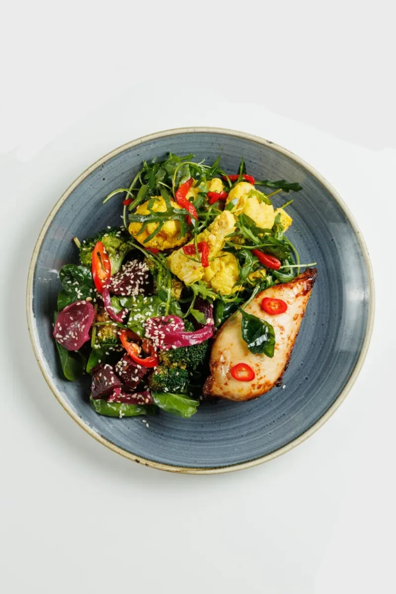 A colourful salad and a chicken breast on a grey plate