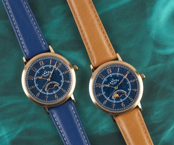 Two watches with starry sky faces, one with a blue strap and one brown
