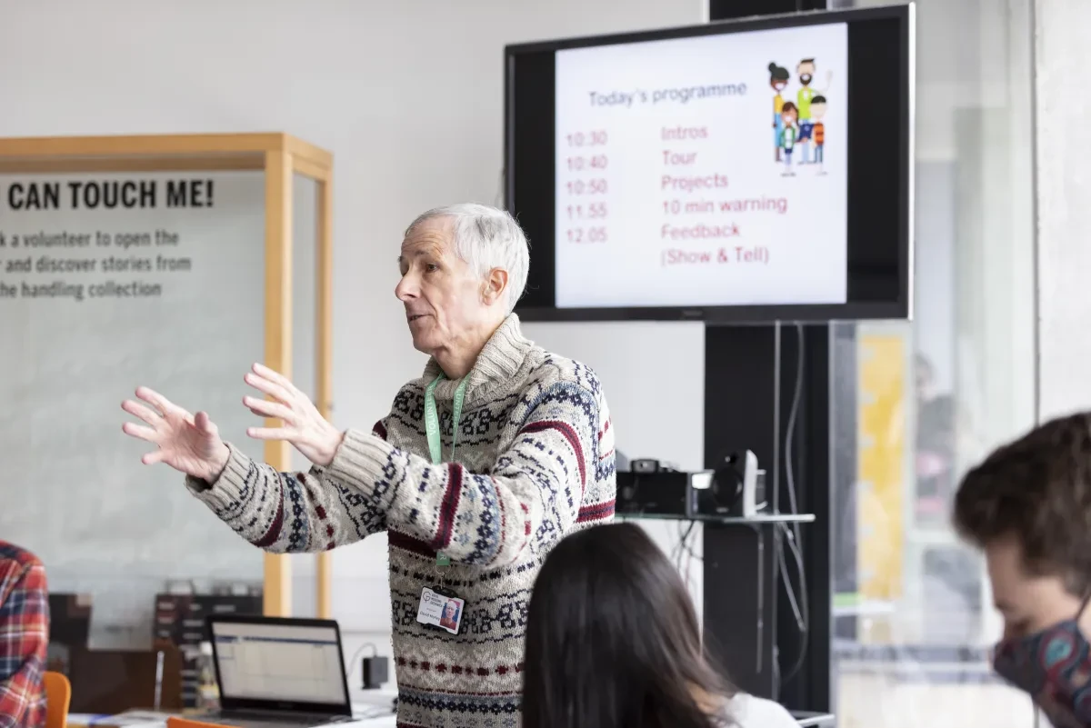 Man standing with his hands raised in front of him speaking to an audience 