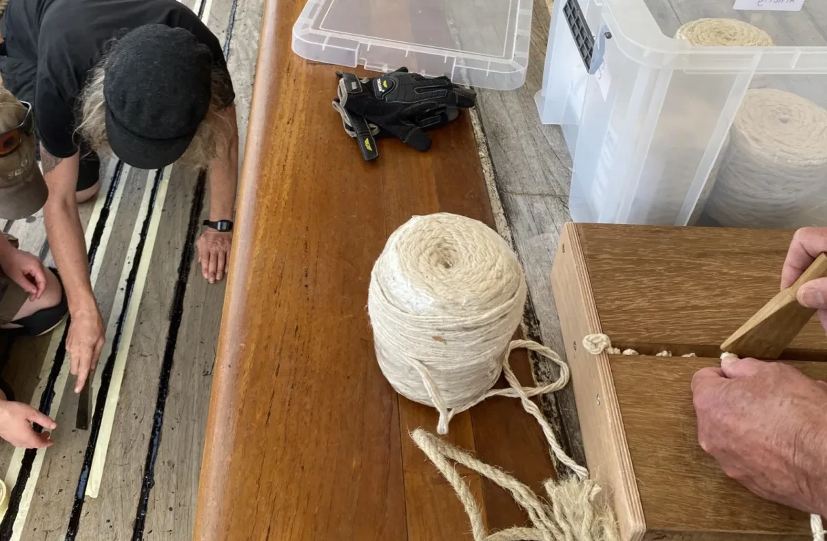 Photo showing on the left hand side a person caulking the deck of a historic ship, and on the right someone caulking a model deck