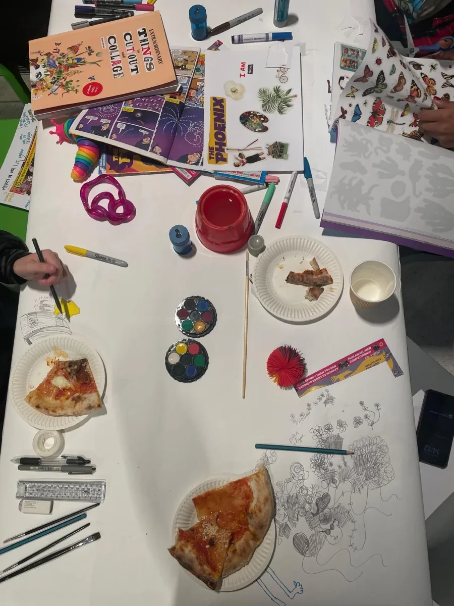 A table with a white table cloth, with people writing and drawing