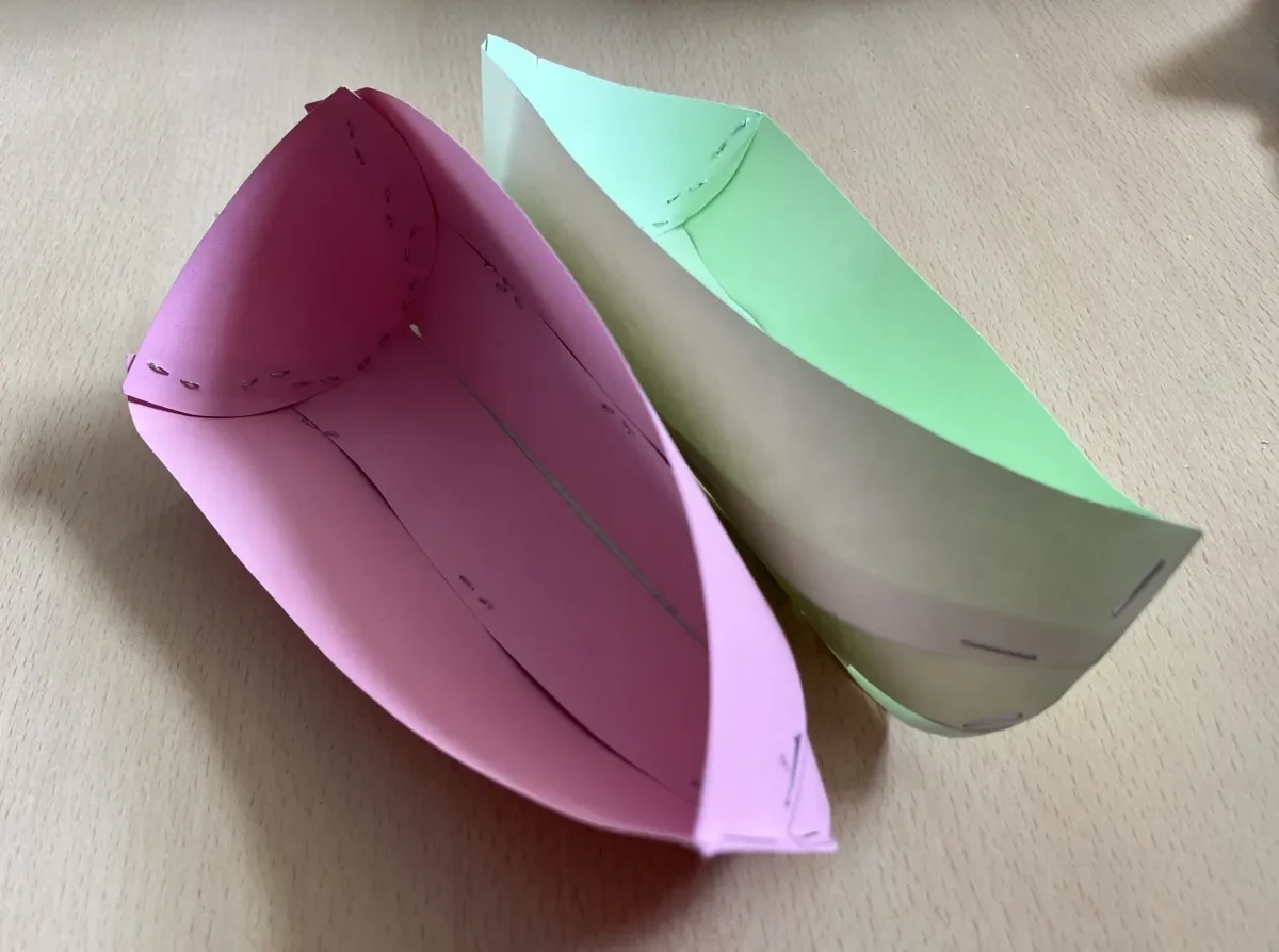 Two paper boats, with the joints and shape held by staples