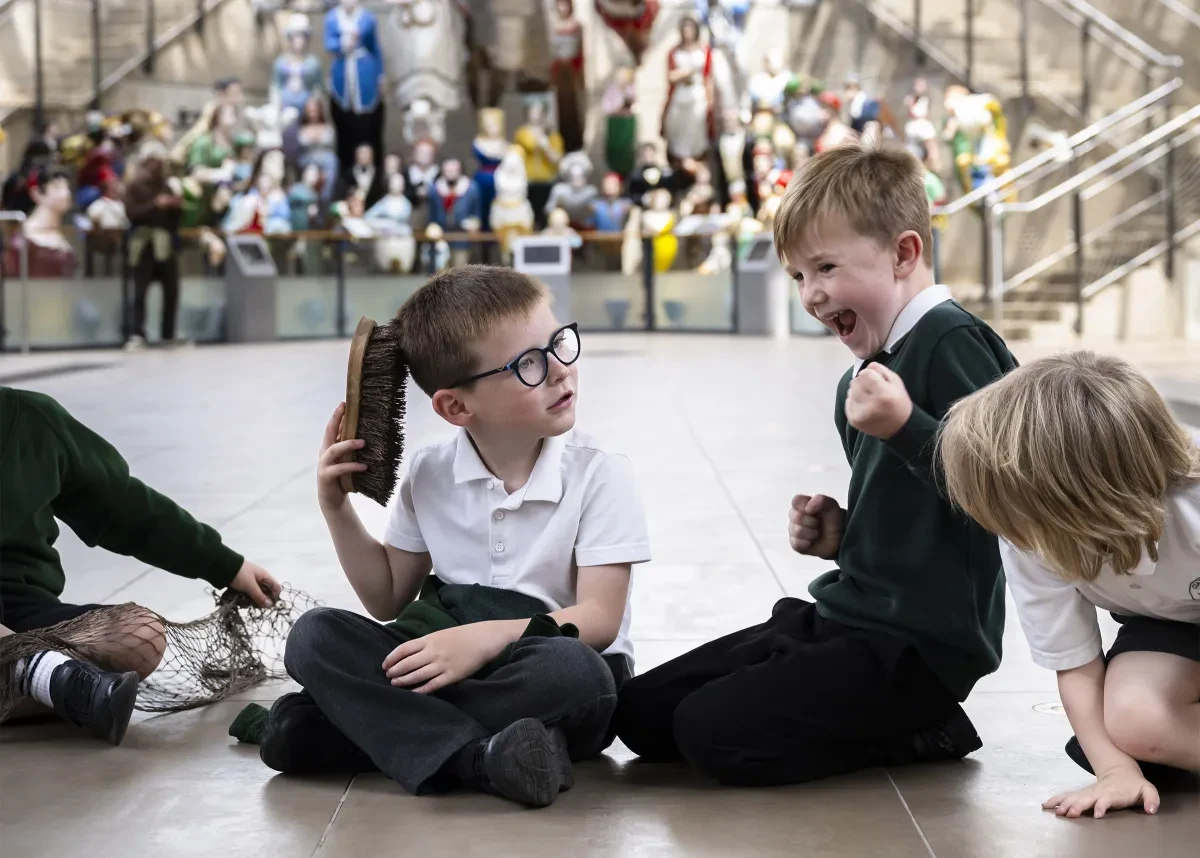 Young children in school uniform play under the hull of Cutty Sark.