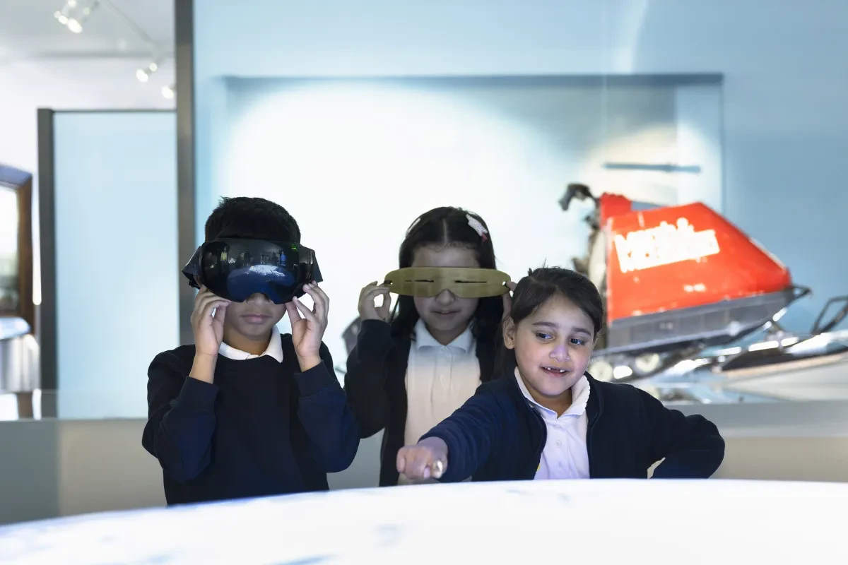 Children in school uniform interact with exhibits in the National Maritime Museum.