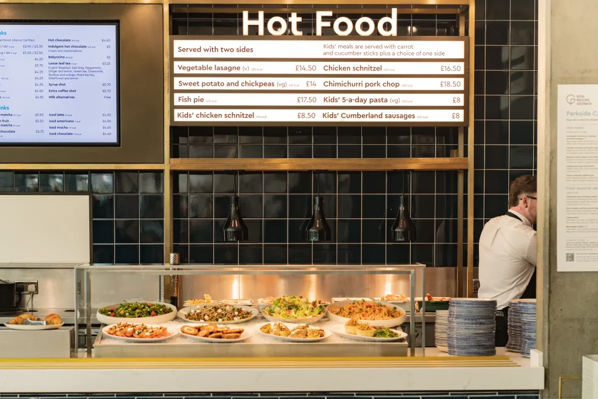The food counter at the National Maritime Museum's Parkside Cafe, with the lit-up Hot Food menu, and salads on display on ice in front